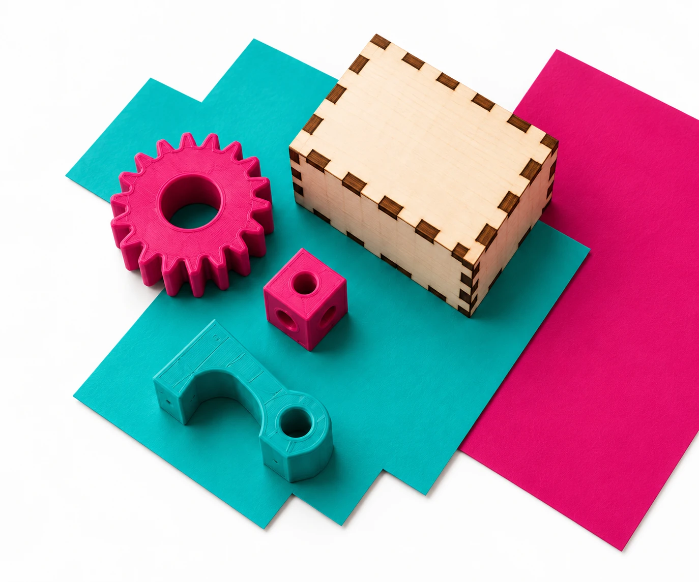 Pièces imprimées en 3D et objets découpés dans le bois, sur des supports magenta et turquoise